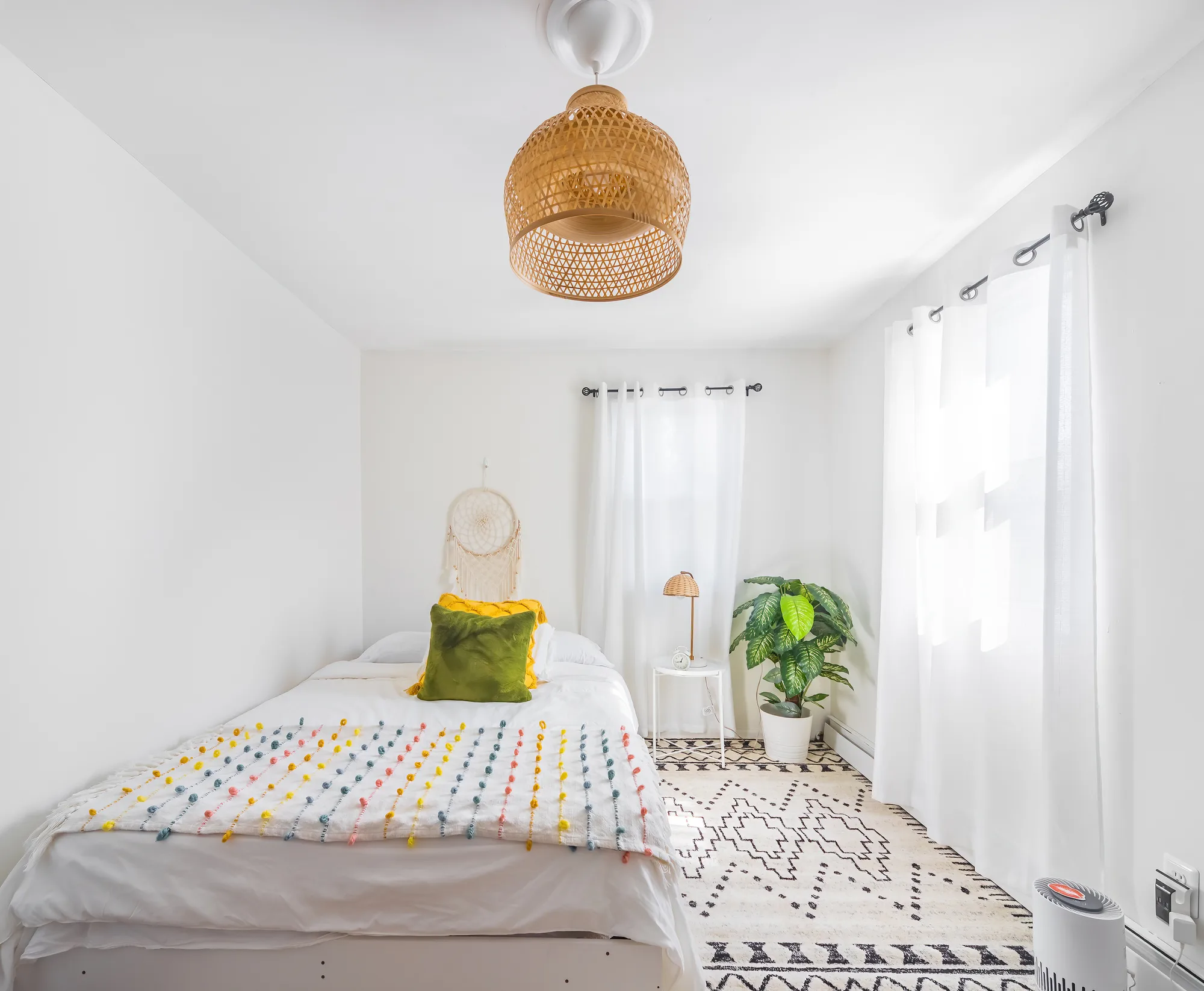 OpenDoors360 professional Airbnb photography of a bright, airy bedroom with a plant and woven light fixture in a short-term rental, shot in the best light to entice potential guests