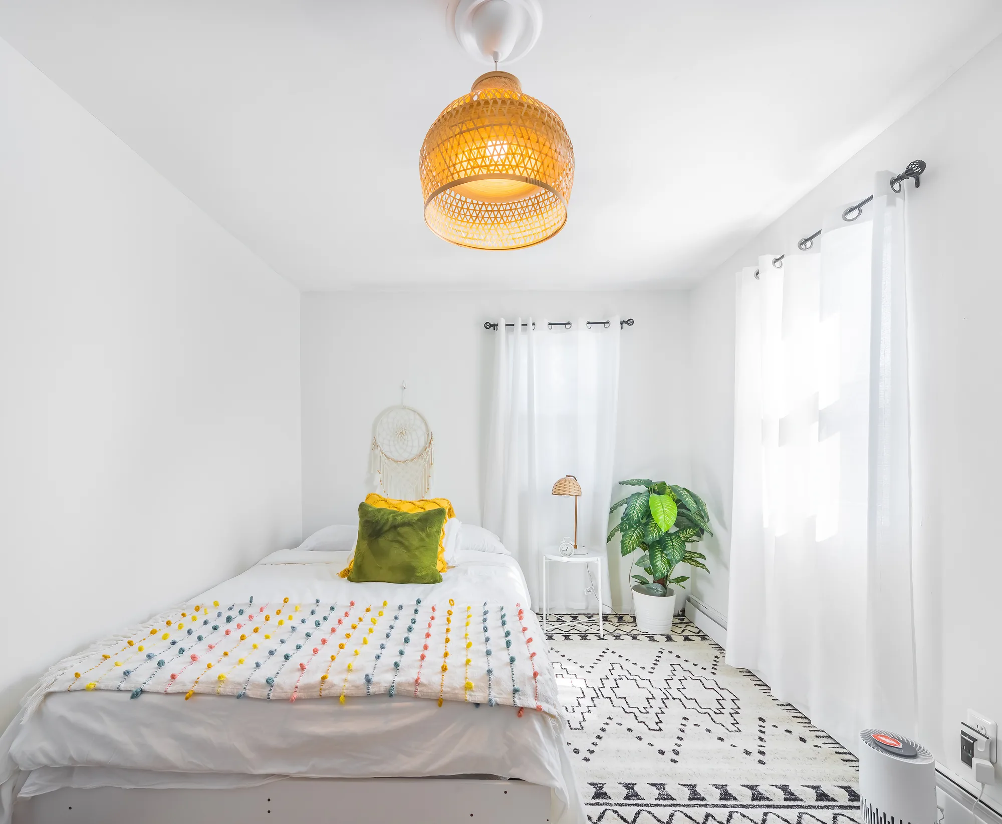 OpenDoors360 short term rental photography of a bright white bedroom with sheer curtains and a woven pendant light in a New York City rental, shot with the window light doing the work
