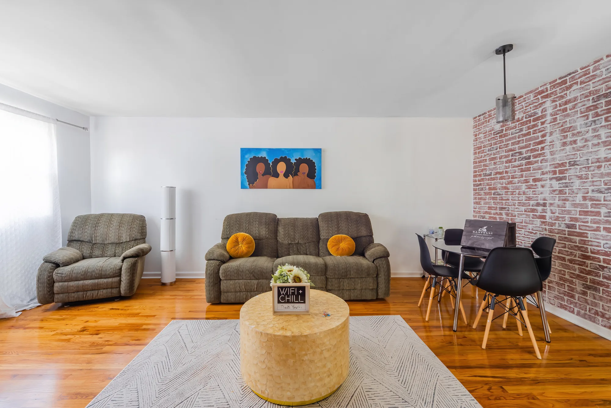 OpenDoors360 professional Airbnb photography of a bright living and dining room with exposed brick in a New York City short-term rental, the kind of airbnb photos that entice potential guests