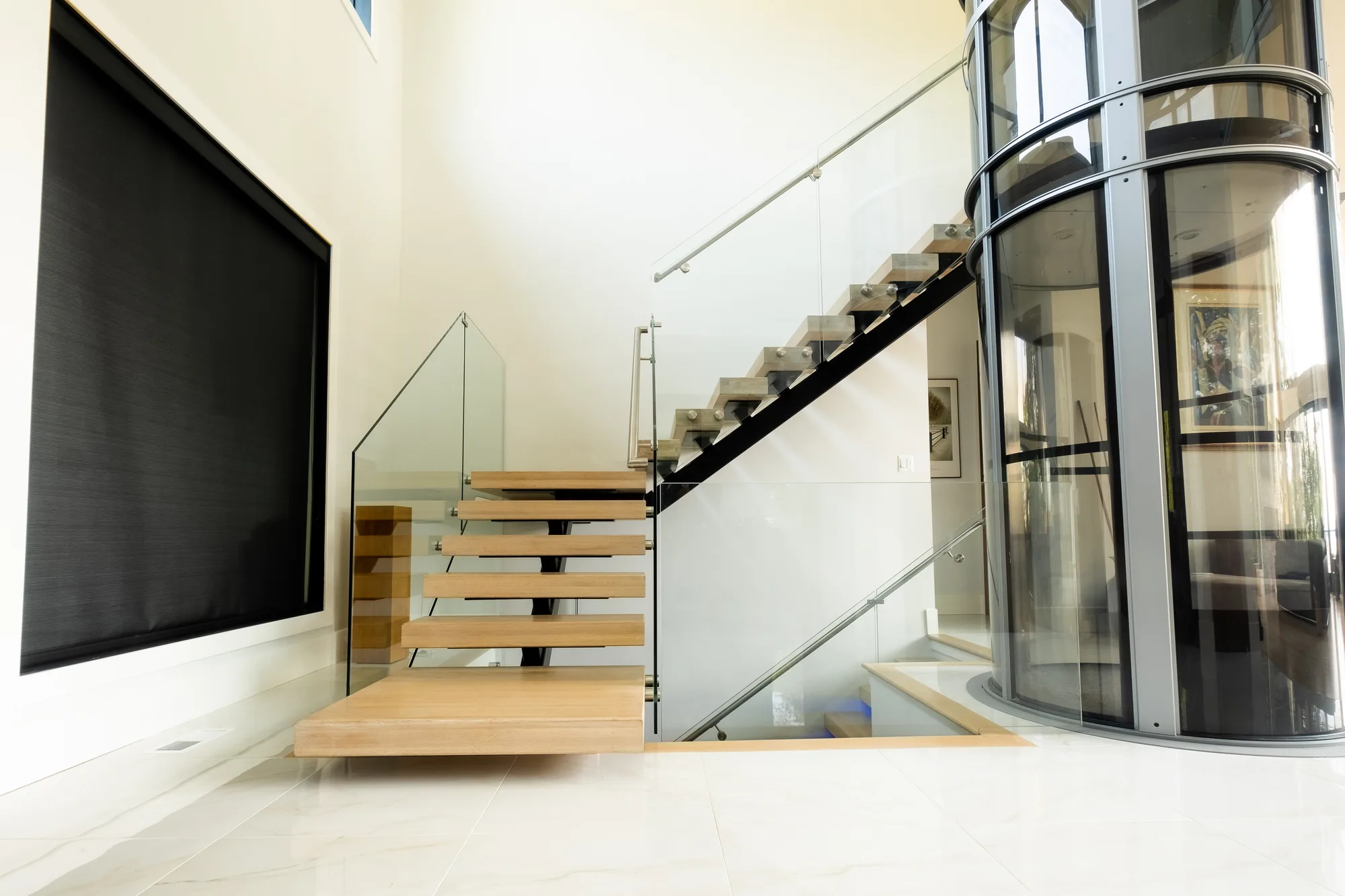 Architectural interior of a New York City commercial property with a floating staircase and glass elevator, captured for commercial real estate photography to highlight the unique features and finish of the office space