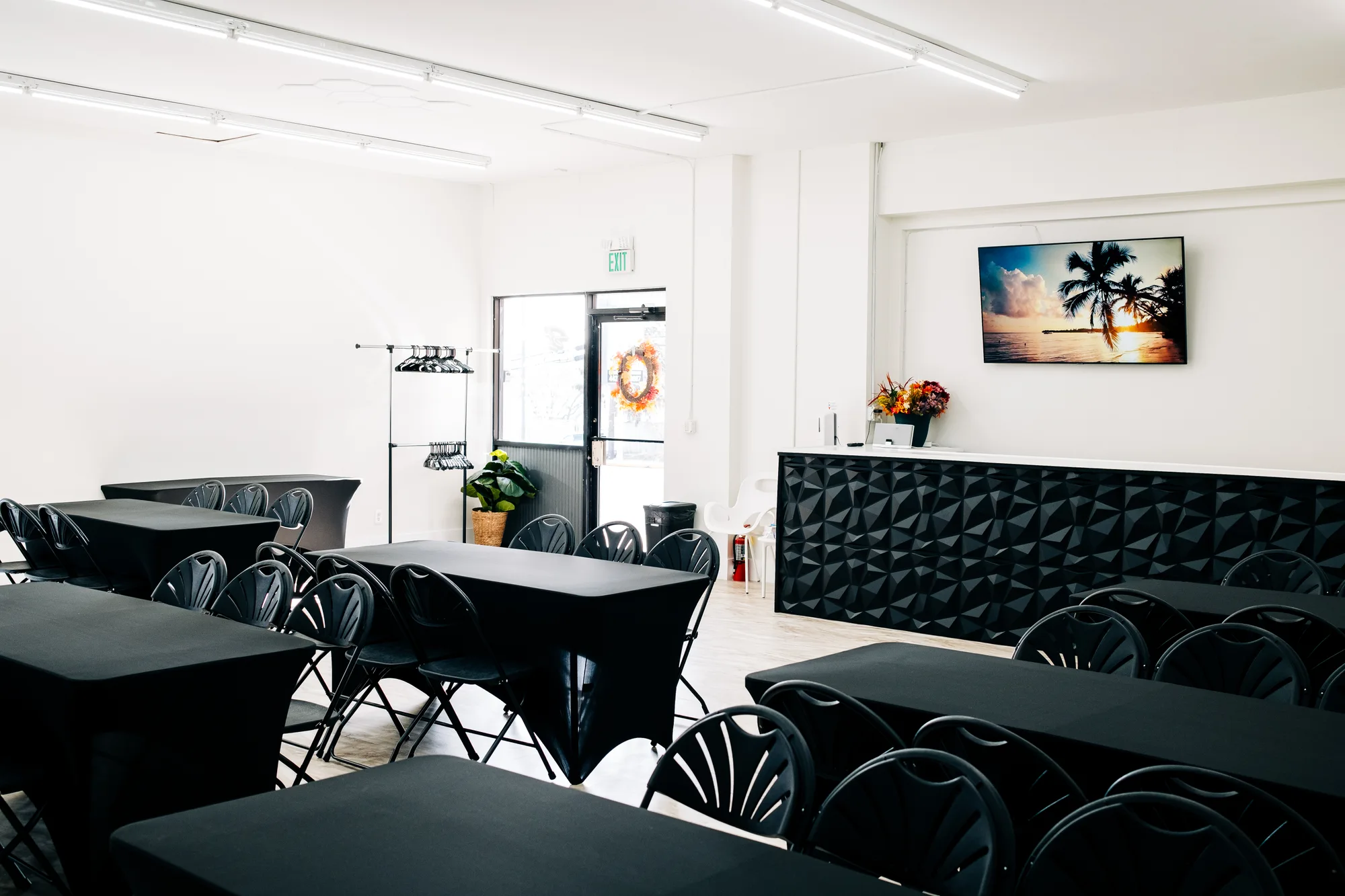 Black-linen banquet tables, geometric bar and tropical wall art set for an event at Studio 87, by OpenDoors360