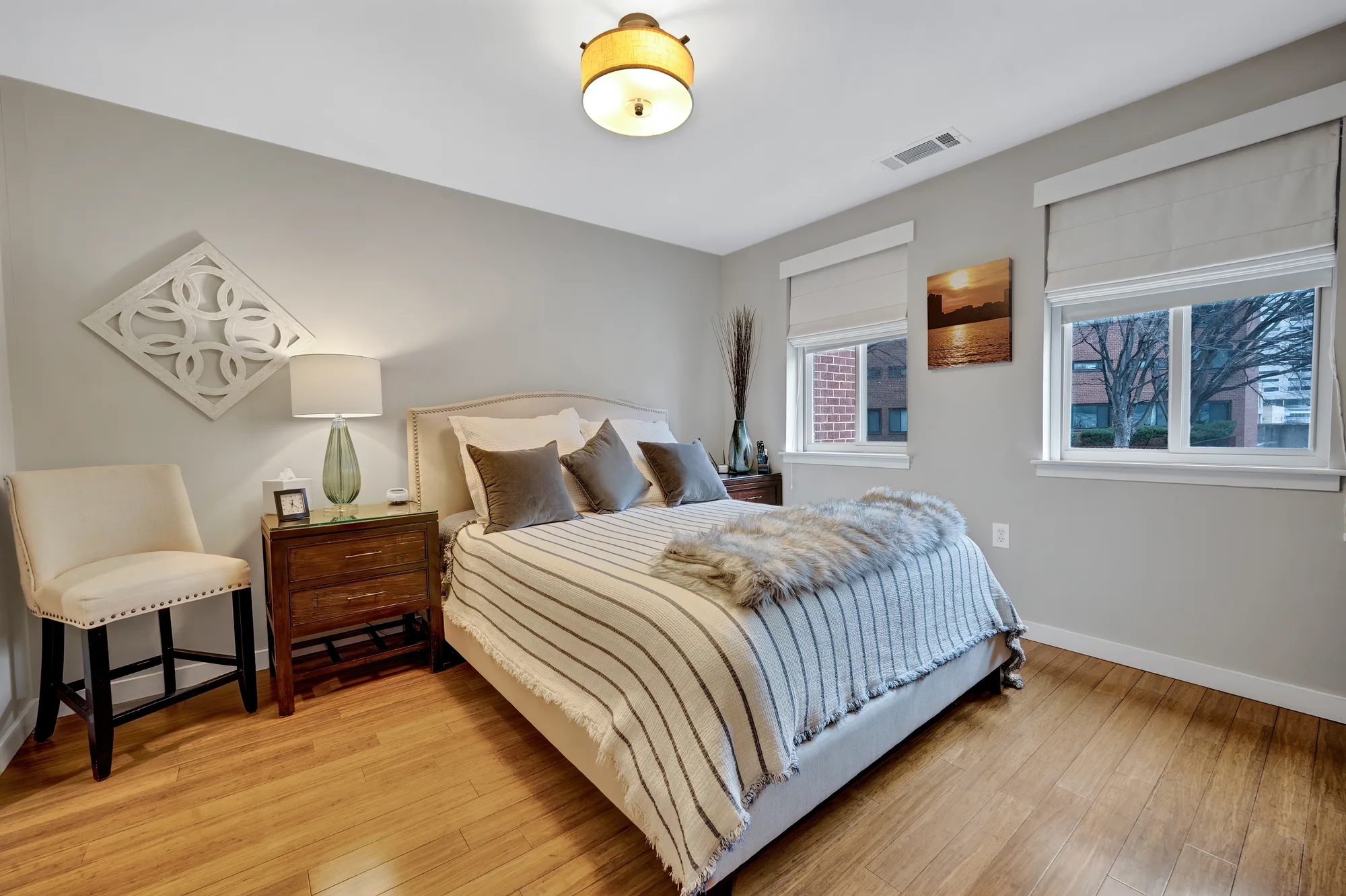 Bright bedroom with upholstered bed, hardwood floors and fur throw, real estate photography, by OpenDoors360
