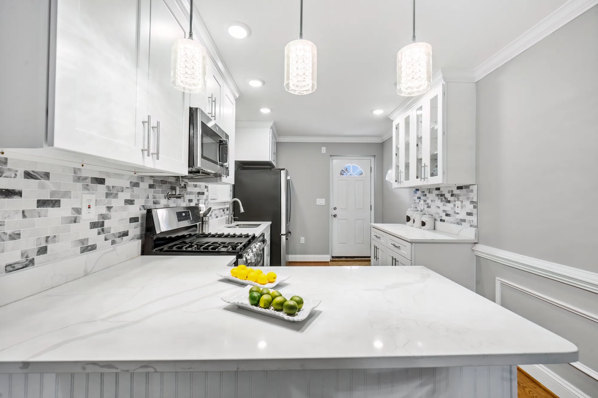 Kitchen with white cabinets, marble counters and pendant lights in Baltimore, MD, by OpenDoors360