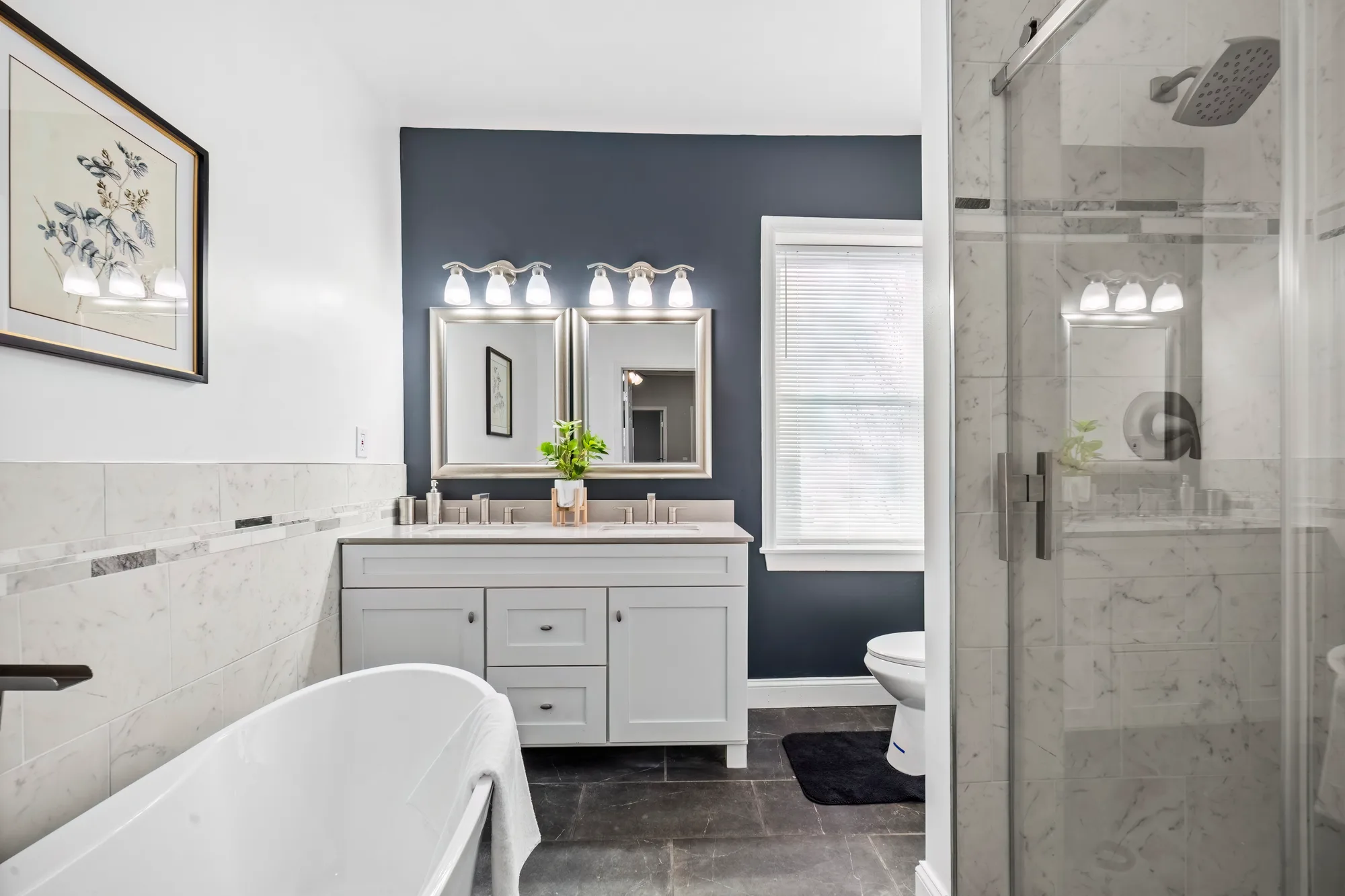 Bathroom with freestanding tub, double vanity and navy accent wall in Baltimore, MD, by OpenDoors360