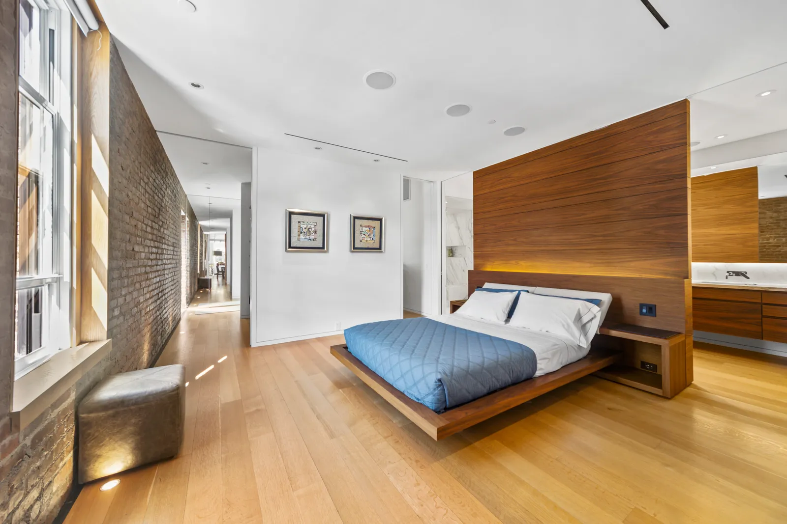 Bedroom with a platform bed against a walnut headboard wall beside exposed brick, SoHo, New York City, by OpenDoors360