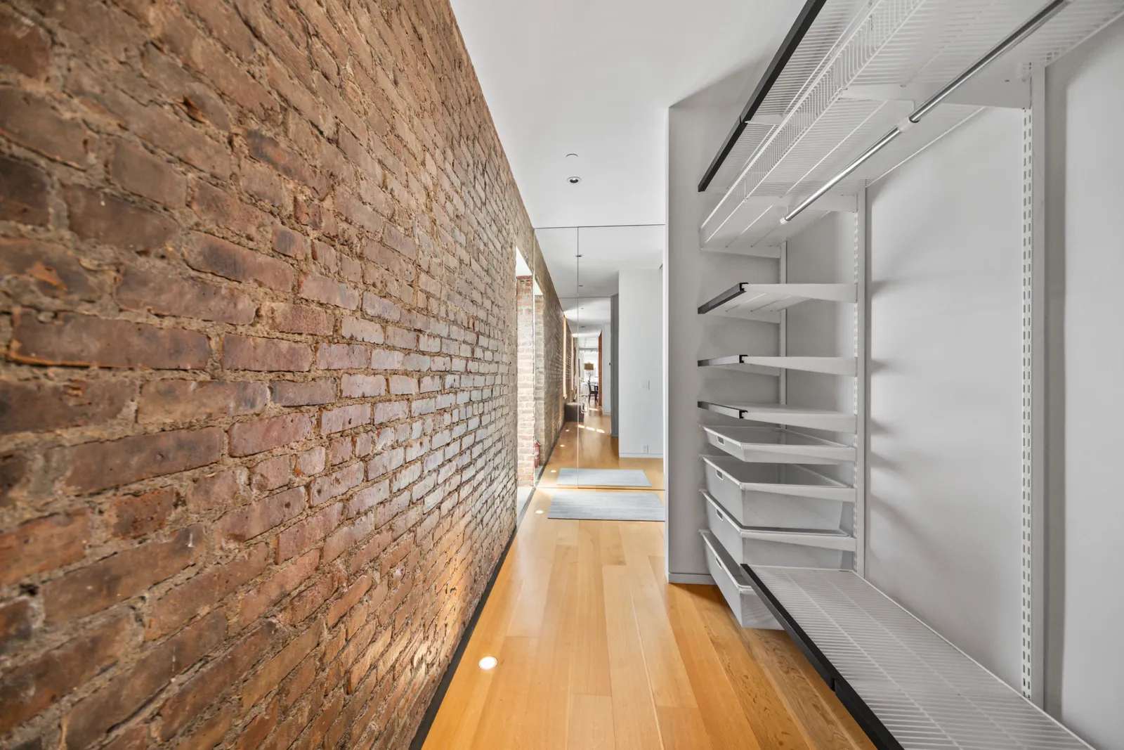 Hallway along an exposed brick wall past open closet shelving in a SoHo loft in Manhattan, by OpenDoors360