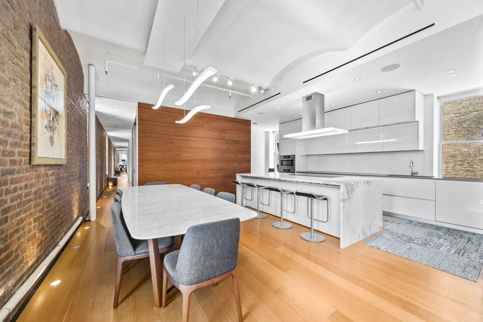 Marble dining table beside a white kitchen island with bar stools in a Manhattan loft, photographed by OpenDoors360 on the same shoot as its video walkthrough