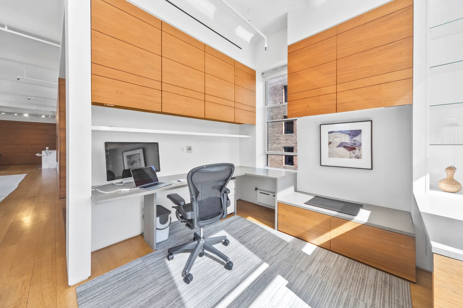 Built-in desk and walnut cabinetry beside a window in a SoHo loft, by OpenDoors360