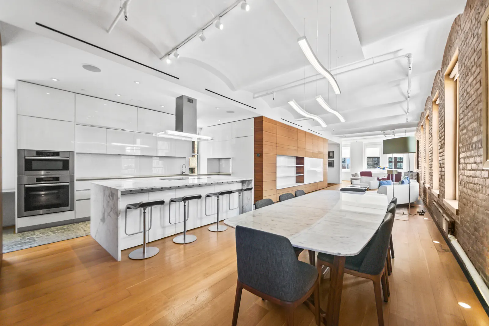 Marble kitchen island and long dining table under exposed brick in a SoHo loft, by OpenDoors360