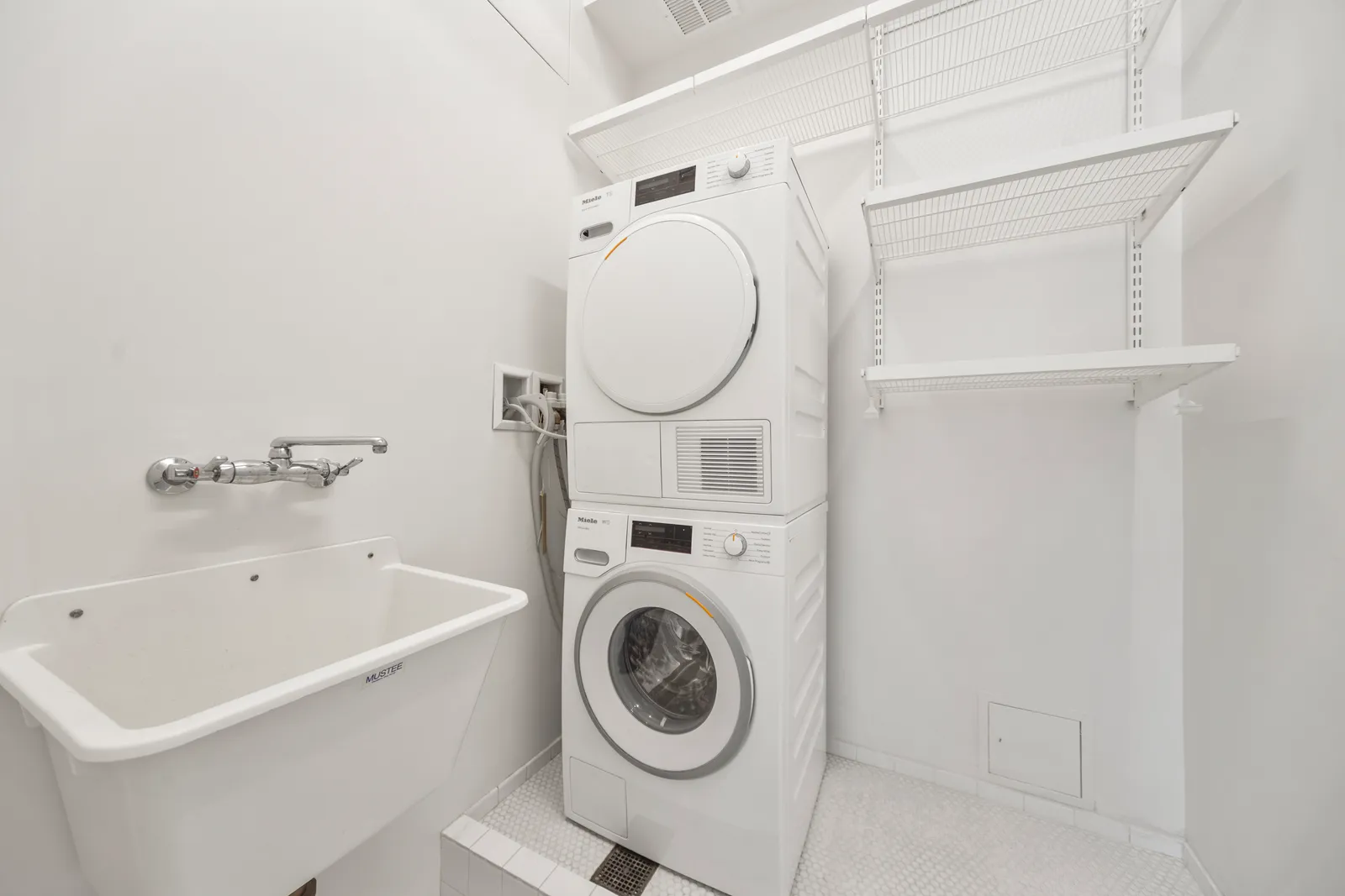 Laundry room with a stacked washer and dryer beside a utility sink in a SoHo loft, by OpenDoors360
