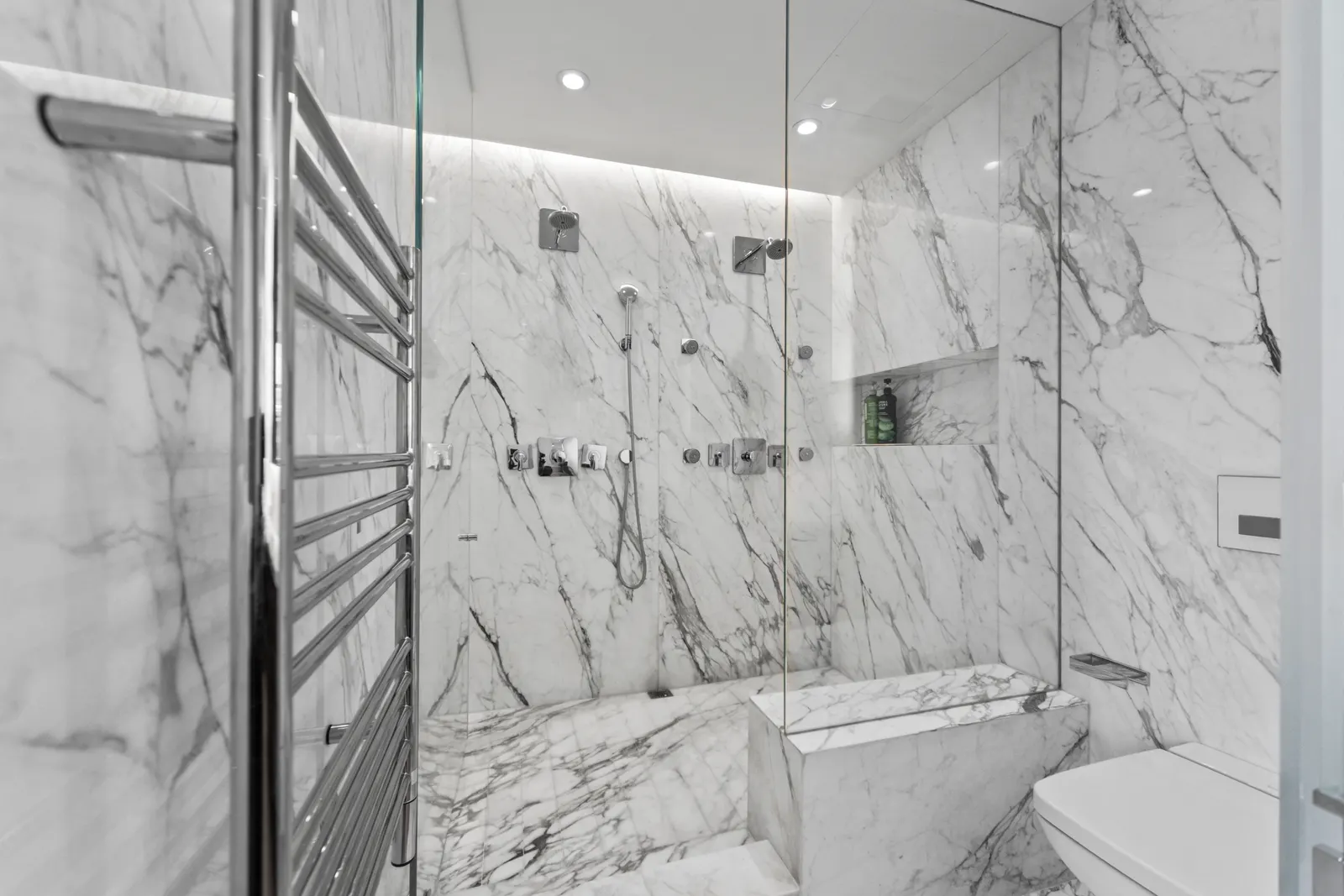 Glass-walled marble shower with a heated towel rail in a SoHo loft, by OpenDoors360