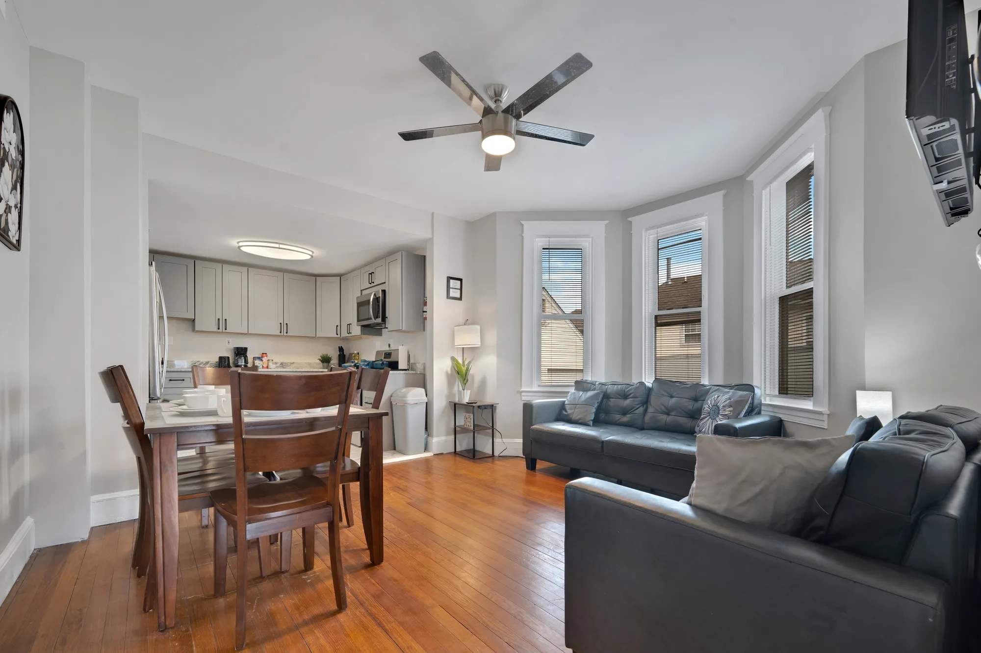 Living room with bay window, leather sofas and dining area in Baltimore, MD, by OpenDoors360