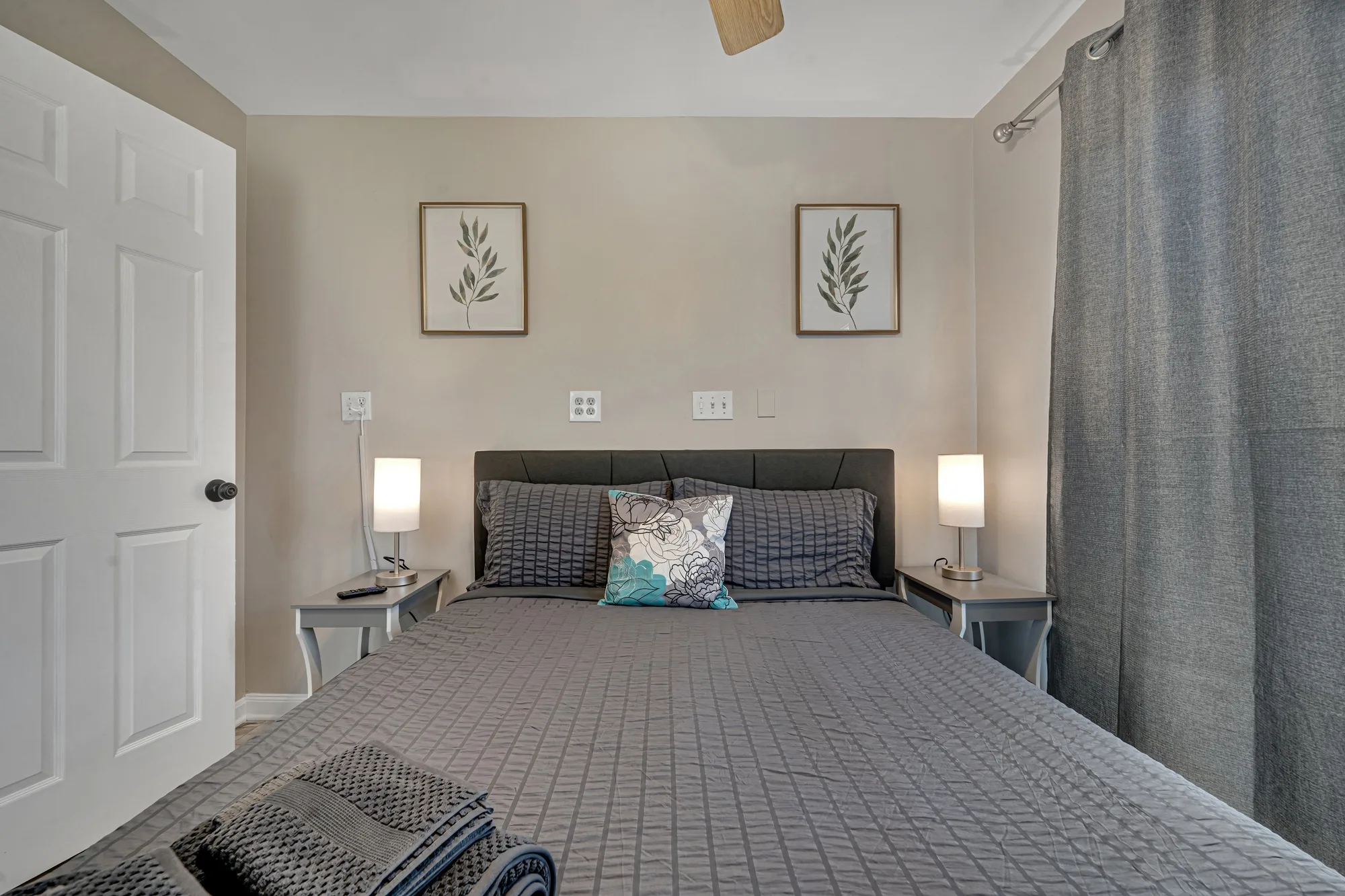Bedroom with gray bedding, twin nightstand lamps and botanical prints in Baltimore, MD, by OpenDoors360