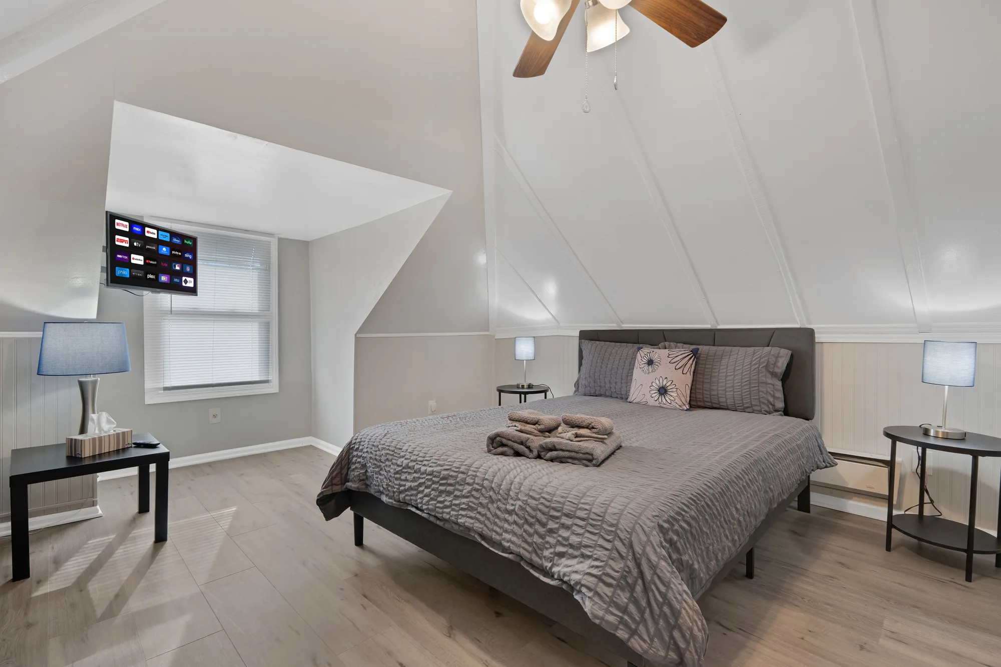 Attic bedroom with vaulted ceiling, gray bedding and wall-mounted TV in Baltimore, MD, by OpenDoors360