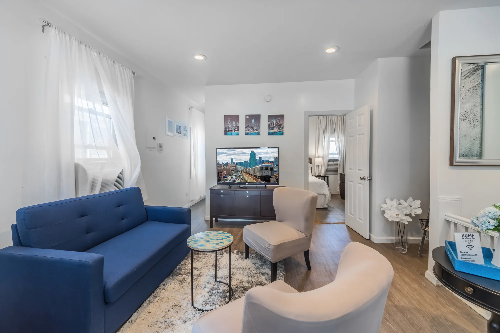 Living room with blue sofa, accent chairs and city skyline art in Queens, NY, by OpenDoors360