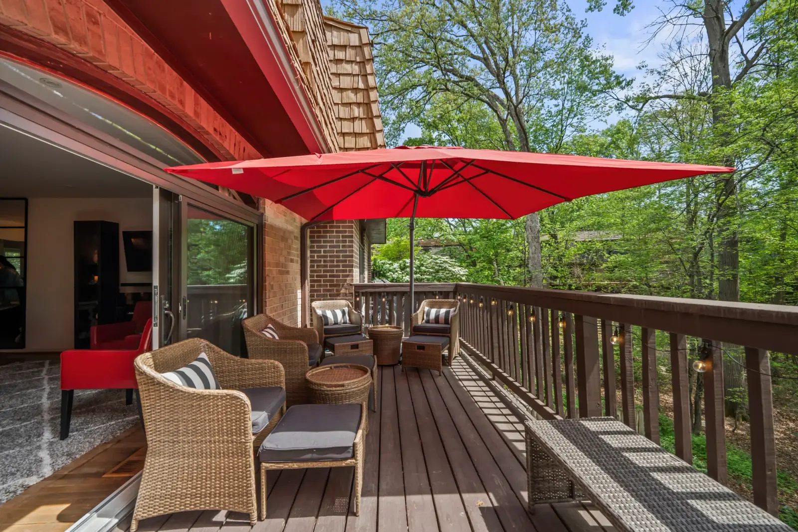 Wraparound wood deck with red umbrella and wicker seating among trees in Northern Virginia, by OpenDoors360