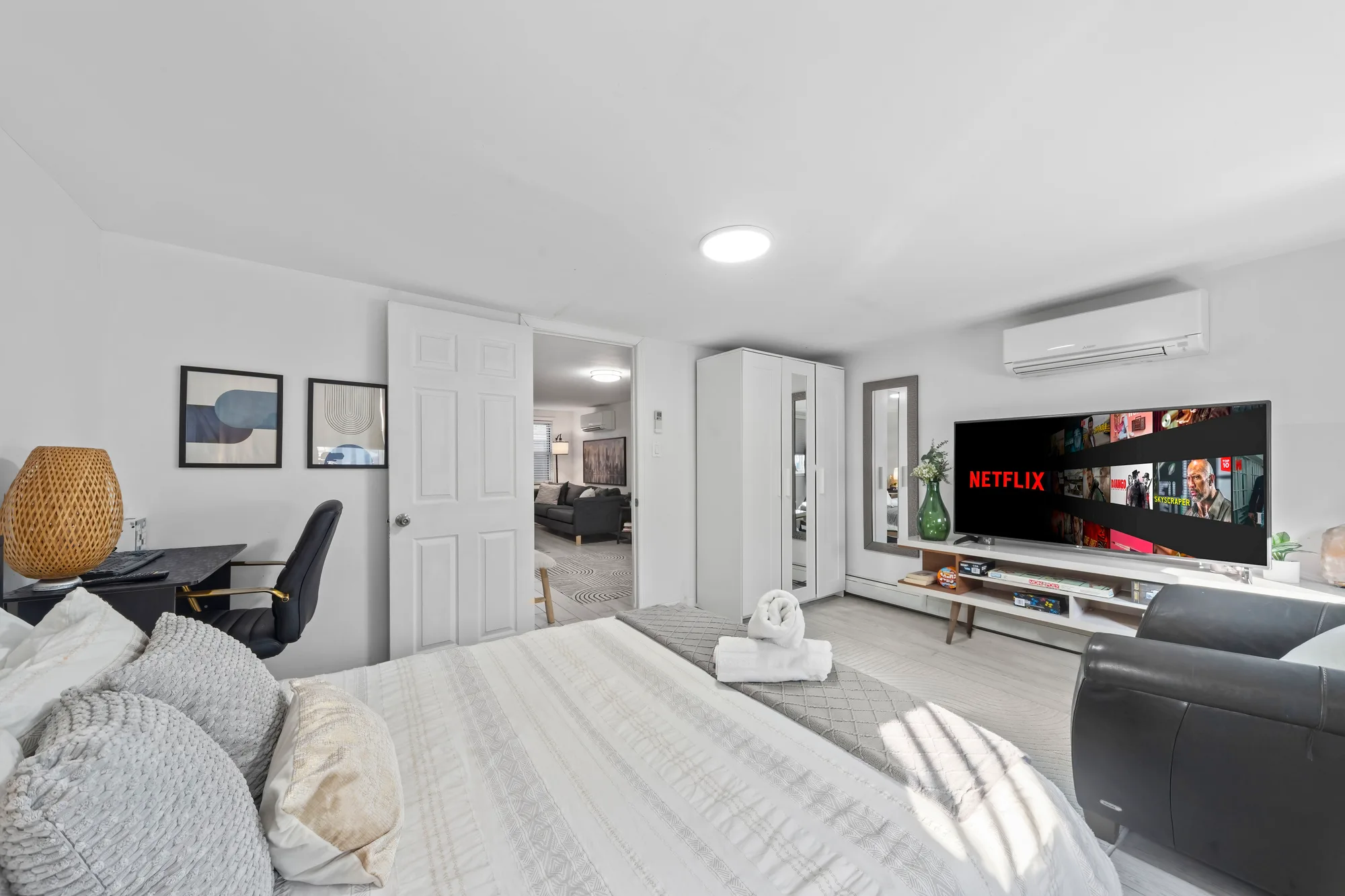 Bedroom with desk nook, mounted TV and rolled spa towels on the bed, by OpenDoors360