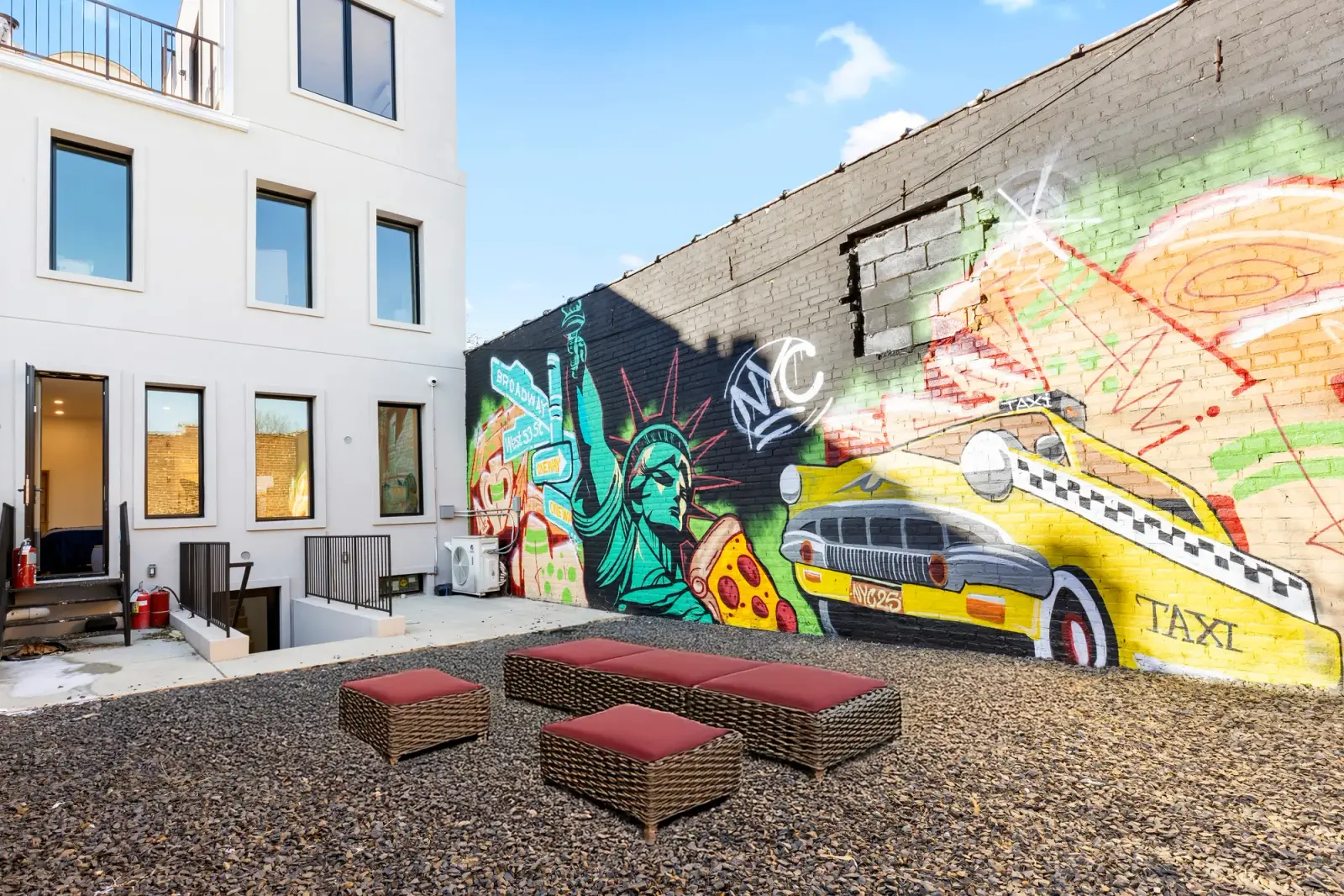 Outdoor courtyard with a New York City mural behind a Bronx apartment building, exterior real estate photography in NY
