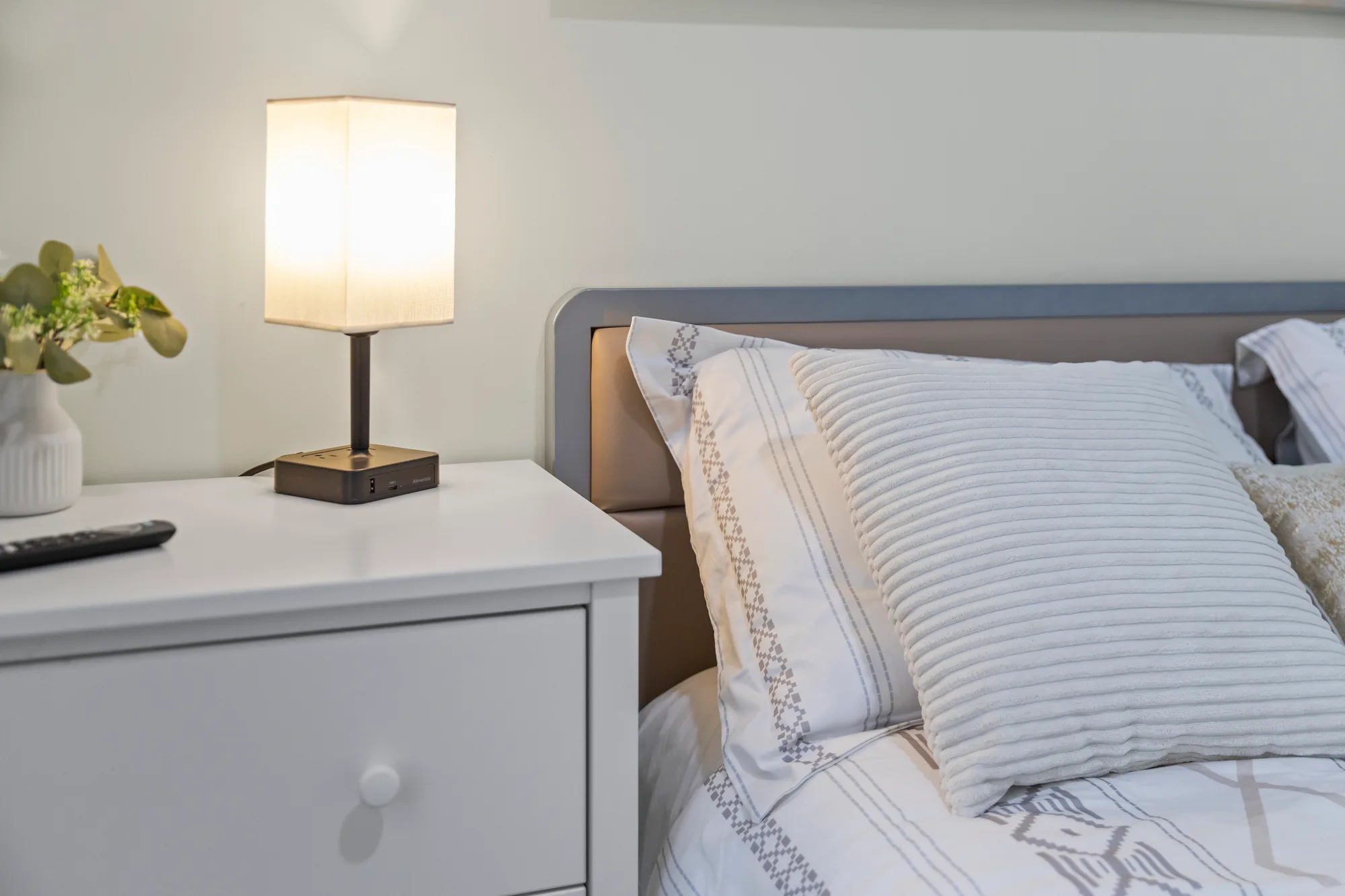 Nightstand detail with a USB charging lamp in a New York City short term rental, professional photographers capture the unique details and amenities for a Vrbo listing