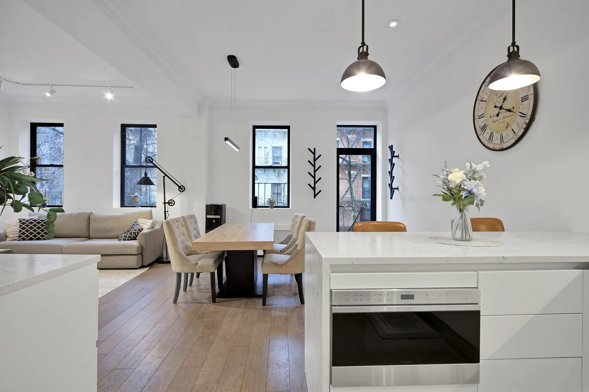 Open kitchen and dining area with New York City apartment buildings out the windows, HDR real estate photography for a Bronx listing