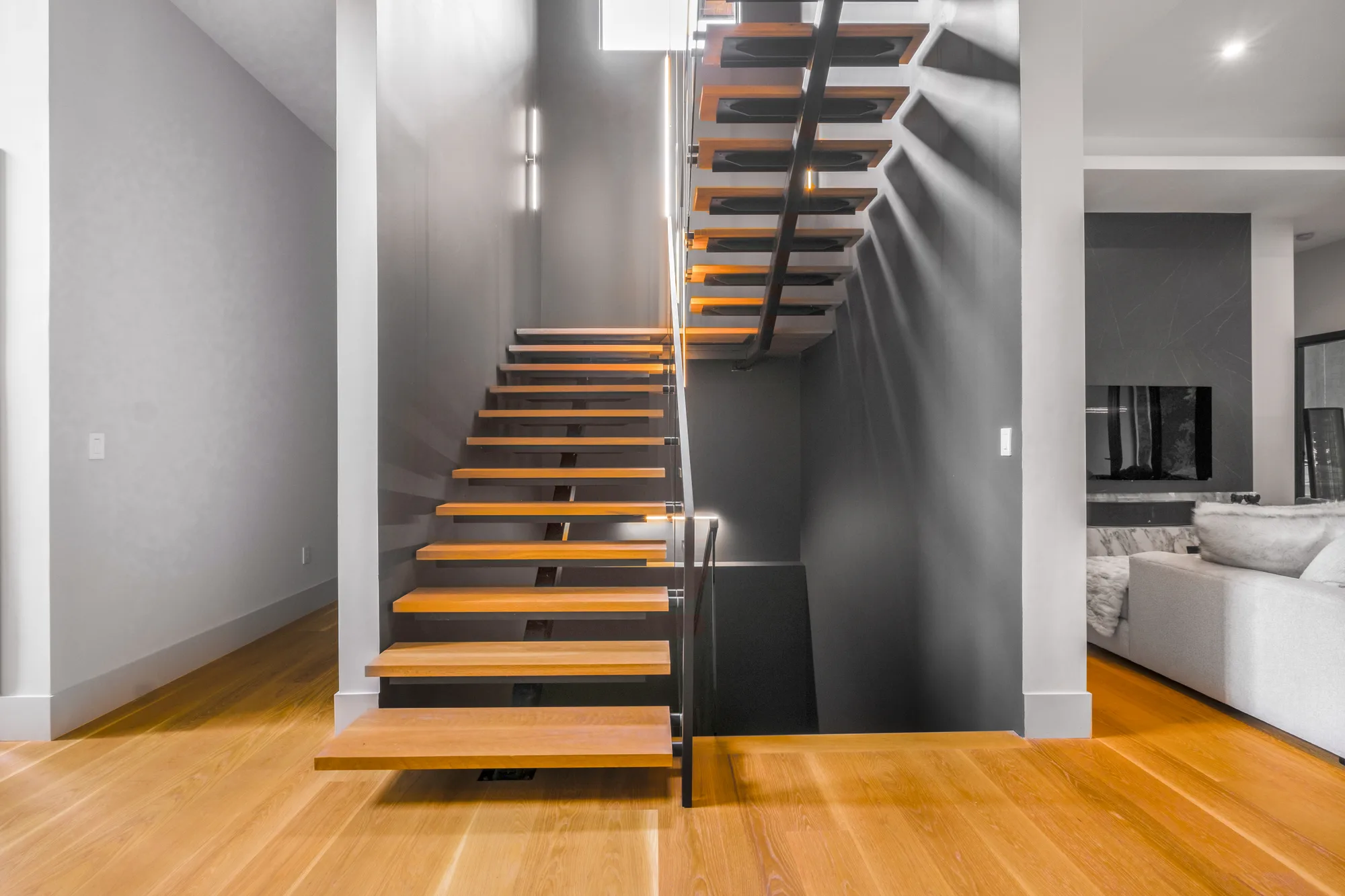 Floating wood staircase with glass railing and LED lighting in modern open-concept home, by OpenDoors360