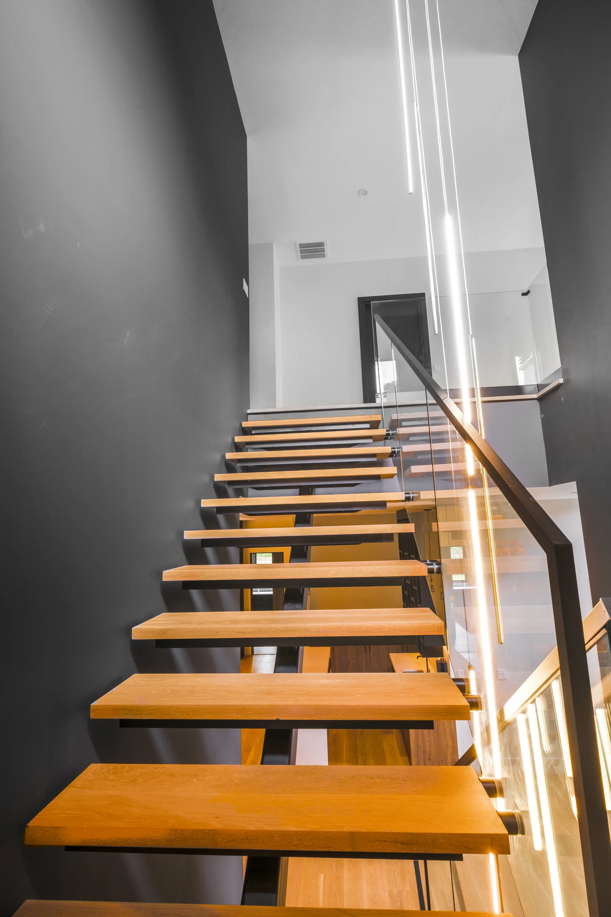 Floating wood staircase against a dark wall, architectural real estate photography on Staten Island that gives a strong first impression on a high-end listing