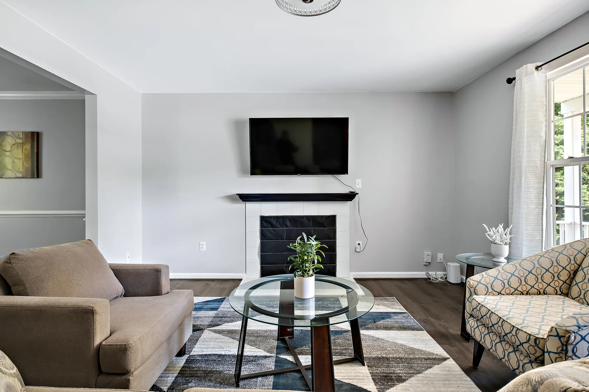 Staged living room with wall-mounted TV over electric fireplace, neutral sofas, and geometric area rug, by OpenDoors360