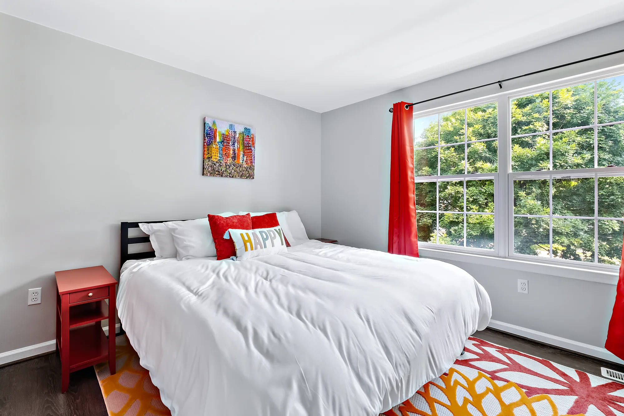 Bedroom with a large window framing green trees, real estate photography for a single-family Staten Island home that markets a quiet suburban setting to buyers