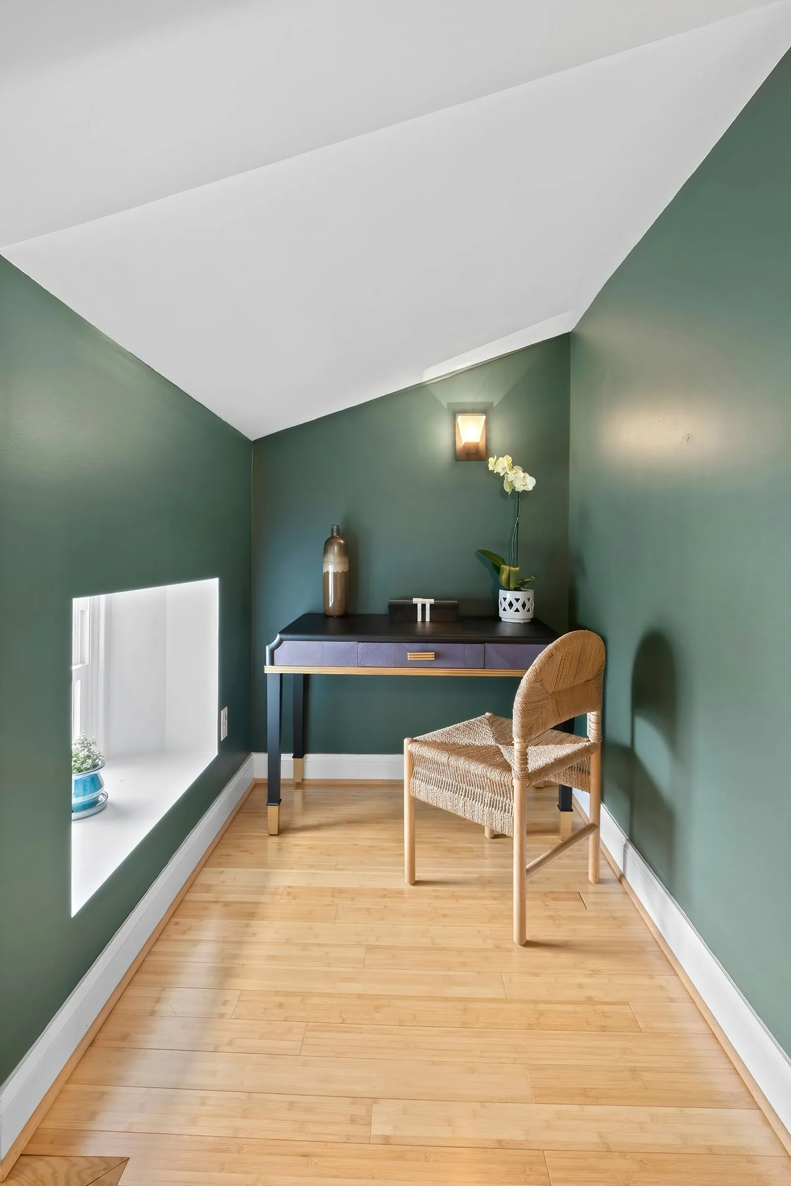 Small home office nook with green accent walls, navy writing desk, rattan chair, and orchid, by OpenDoors360