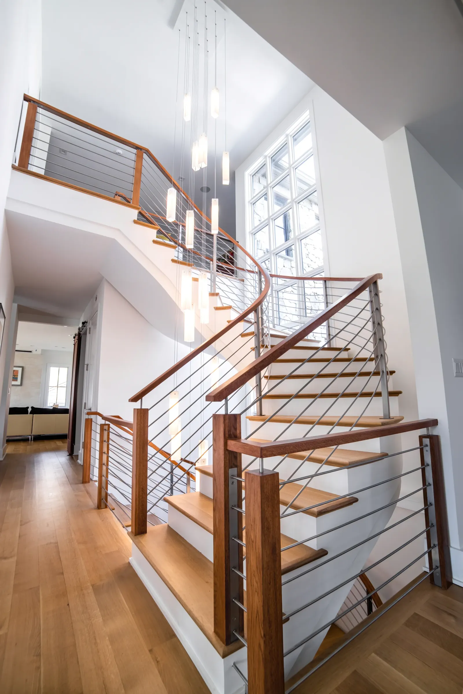 Curved staircase with cable railing and cluster pendant lights in Vienna, VA, by OpenDoors360