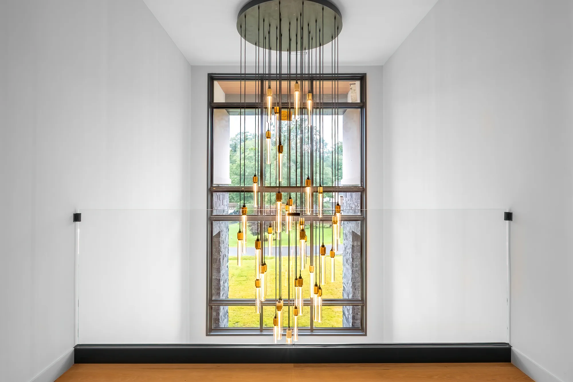 Cascading bulb chandelier in front of a tall window with green view in Clifton, VA, by OpenDoors360