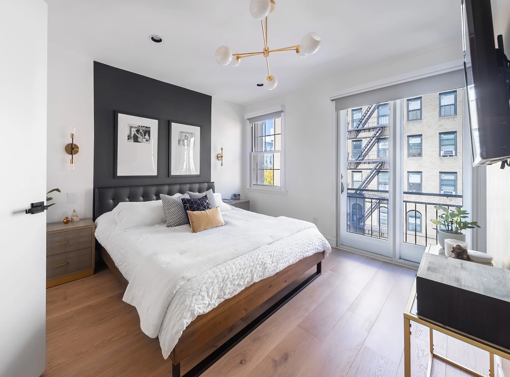 Bedroom with a balcony and a New York City fire escape view in a short term rental, short term rental photography that showcases the property and surrounding area for potential guests
