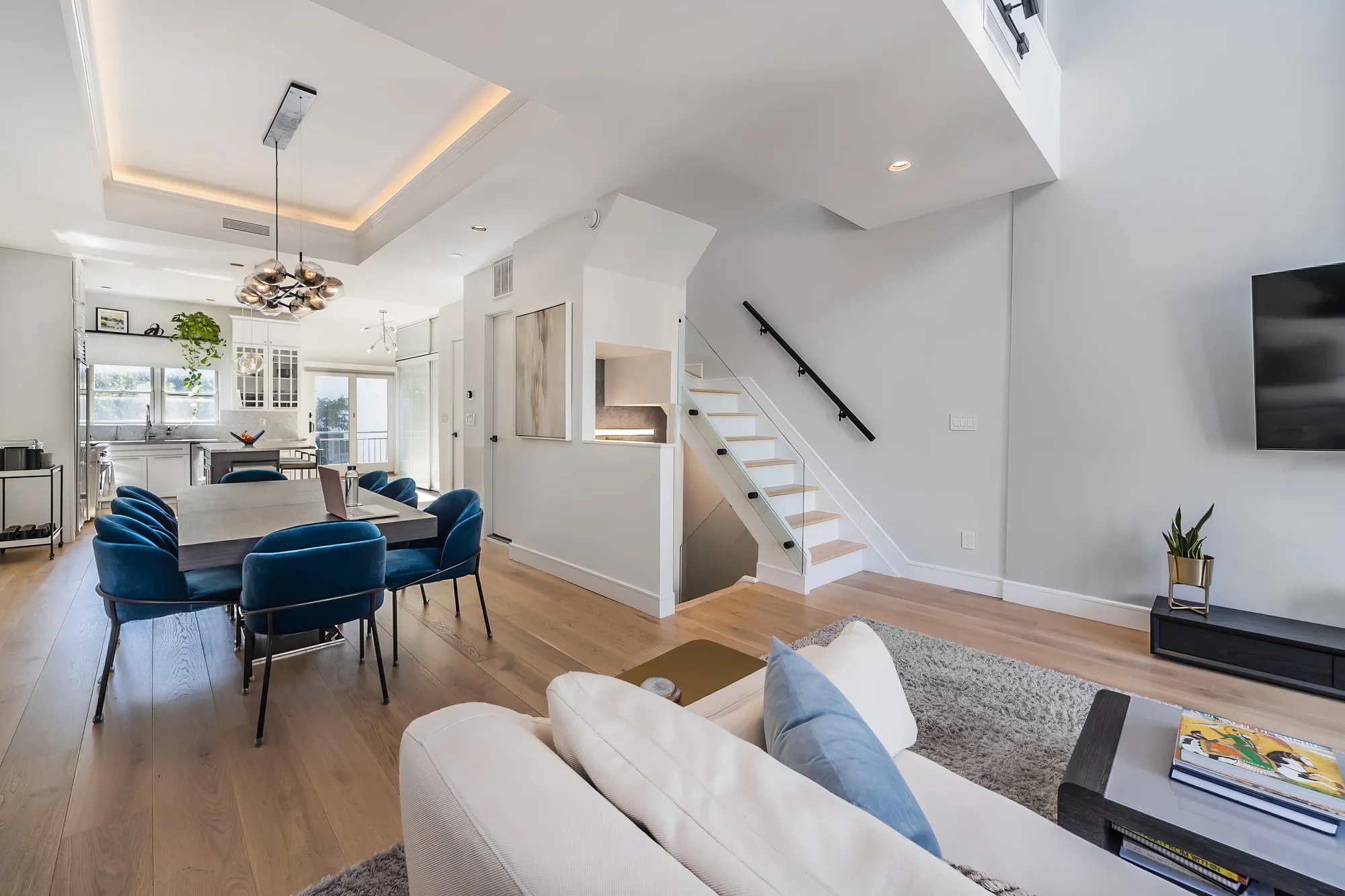 Open-plan living and dining room with stairs in a Queens townhouse, real estate photography for New York City listings