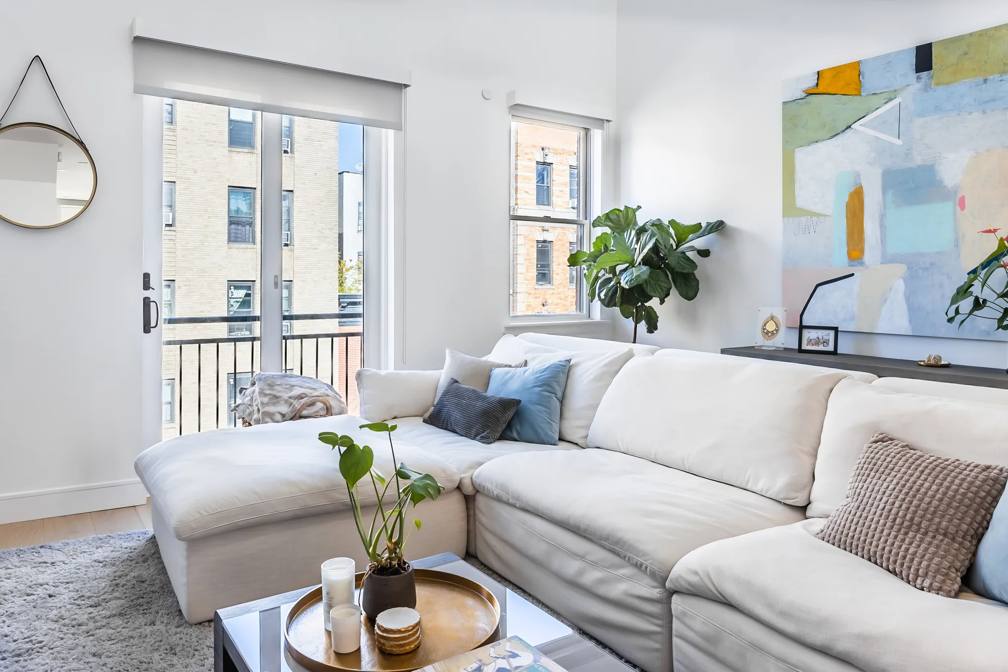 Bright living room with the surrounding New York City apartments framed in the window, real estate photography for a Bronx listing