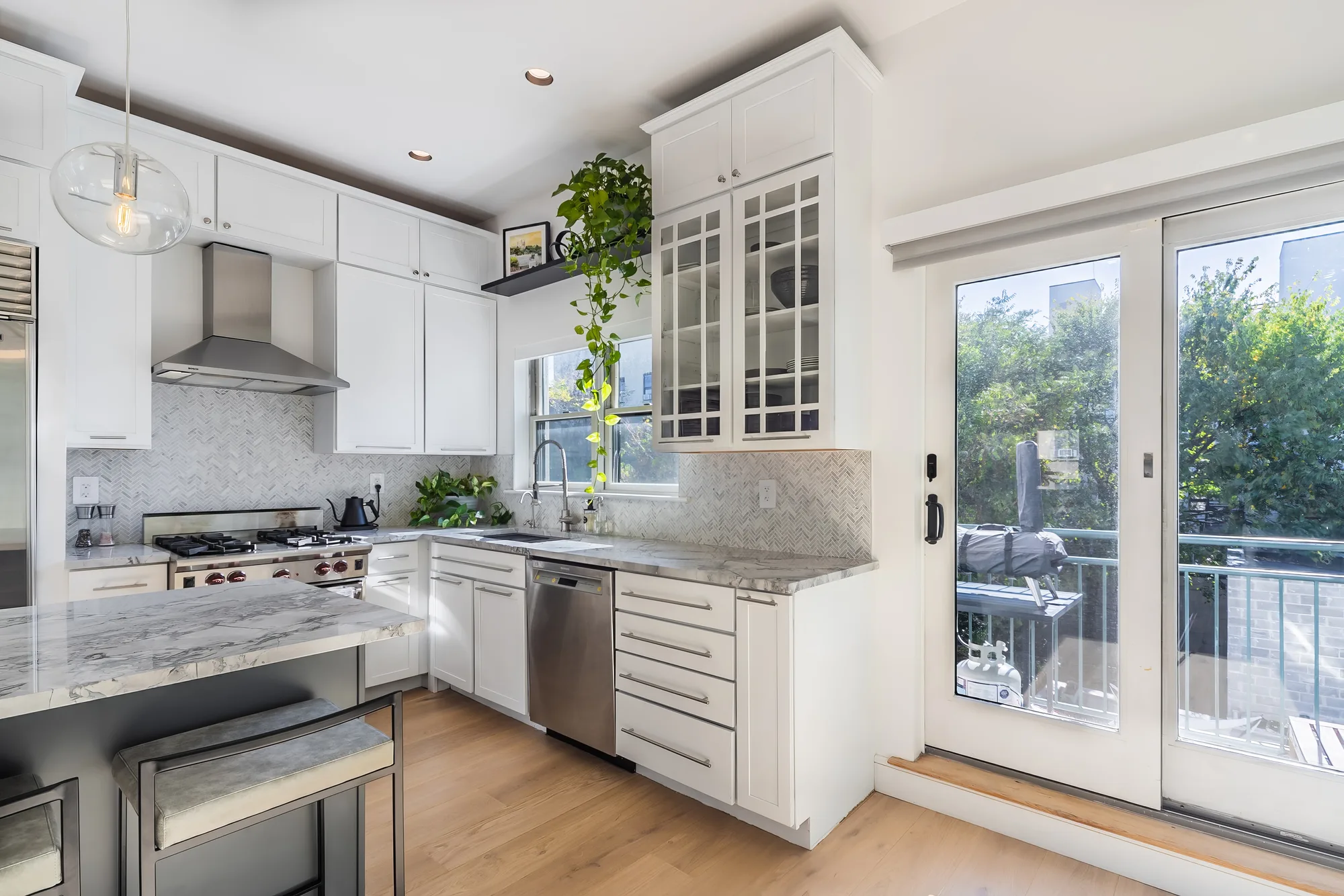White kitchen with balcony doors framed for a real estate video walkthrough in Brooklyn, New York