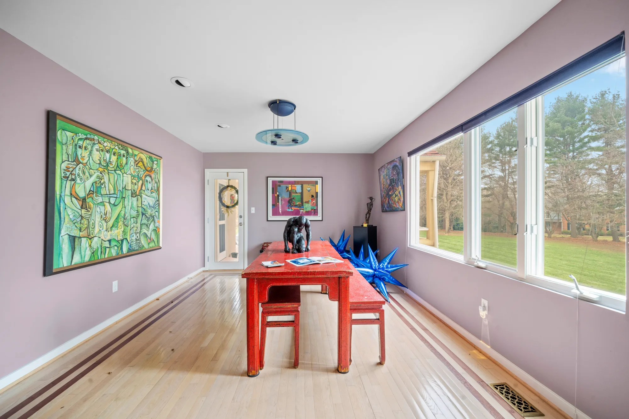 Study with red work table, mauve walls and large green figural painting beside a garden window, by OpenDoors360